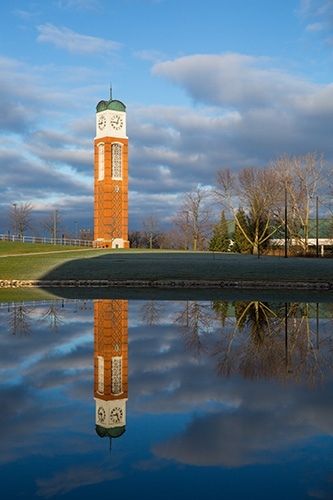 Clock tower and reflection in pond at sunrise